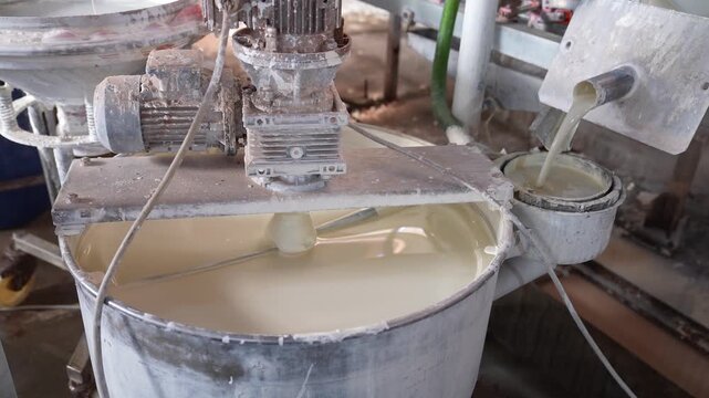 Liquid clay slurry mixing inside industrial ceramic factory tank