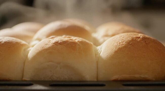 Golden brown fresh baked bread rolls with steam rising, hot from the oven.
