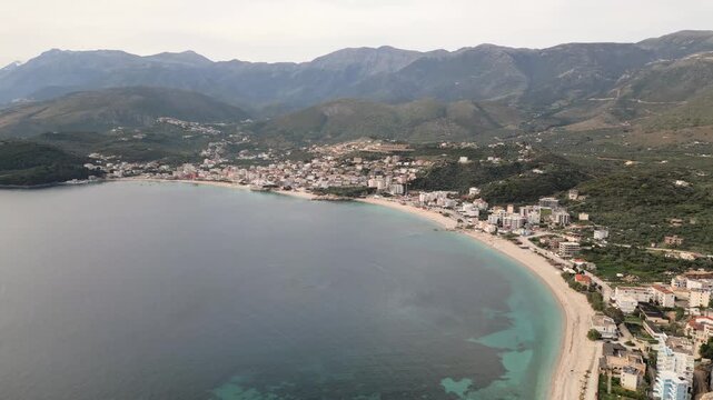 Scenic aerial view gentle calm waves and pebbled shoreline at Himara Beach along the stunning Albanian Riviera. A perfect relaxing Mediterranean travel destination in EUROPE