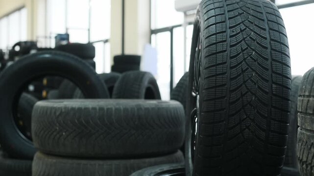 Close-up view of four stacked black car tires showcasing detailed tread patterns and textures in a well-lit automotive workshop environment