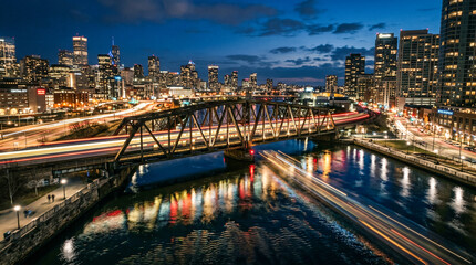 Obraz premium Vista nocturna de tren iluminado cruzando puente sobre río en ciudad, reflejos en el agua, larga exposición, estilo urbano.