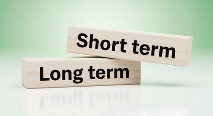 Obraz premium Two wooden blocks with short term and long term on them on green background