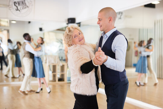 Elderly woman learning ballroom dancing movements in pair