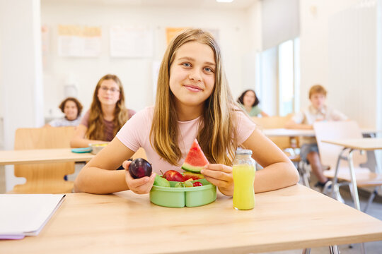 Young student enjoying healthy lunch with fresh fruits in school cafeteria setting