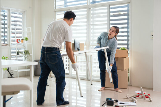 Couple assembly furniture in new house apartment. Relocation lifestyle