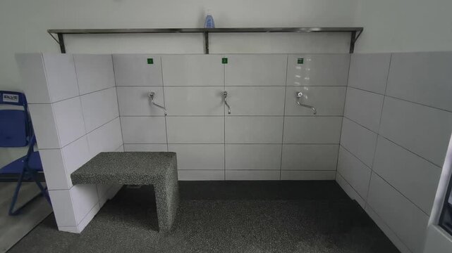 A close-up of a clean ablution area at a small Malaysian highway prayer room. Water flows for ritual washing as travelers prepare for prayer.
