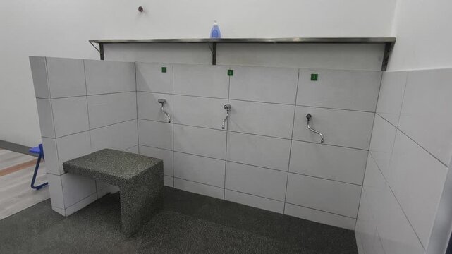A close-up of a clean ablution area at a small Malaysian highway prayer room. Water flows for ritual washing as travelers prepare for prayer.