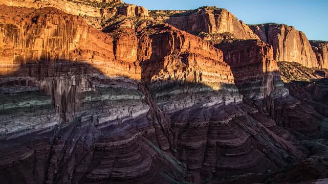 Spectacular layers of red and white rock formations illuminated by golden sunlight in a grand canyon landscape