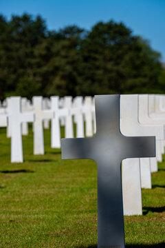 Alignement de croix latines en marbre blanc dans un cimeti&egrave;re militaire verdoyant sous un ciel bleu clair, rendant hommage aux soldats tomb&eacute;s.