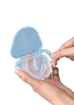 A person holding a clear plastic dental retainer case with aligners