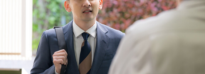 取引先の中小企業に挨拶する信金や外周りの訪問営業マンのビジネスシーン仕事とコミュニケーション　クローズアップ　顔無しのバナー © kapinon