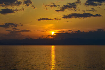 Obraz premium Bright sunset over the ocean with strong reflection path on water and clear horizon line.