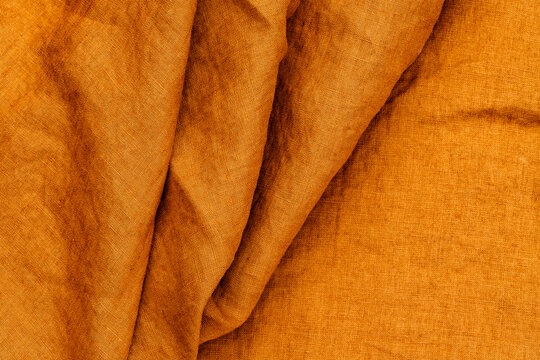 Textured orange fabric draped on a surface in natural light revealing its soft structure and warm tones