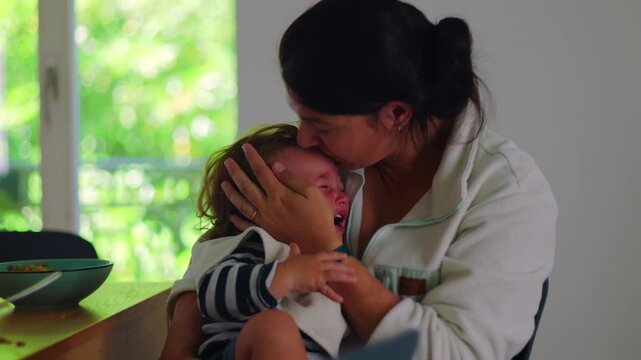 Mother comforting toddler after fall while holding and kissing head, emotional family moment showing protection, reassurance, care, and strong maternal bond during distress