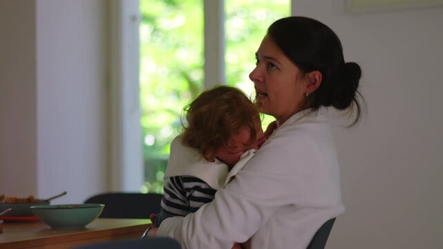 Mother holding crying toddler and speaking firmly after accident, emotional parenting moment showing discipline, concern, and guidance while maintaining protective and caring presence