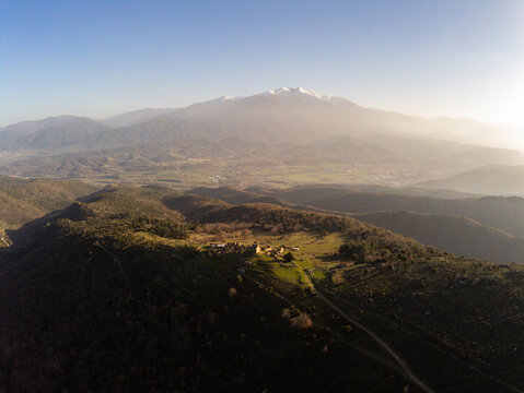 Aerial view of the ruins of Comes village on a mountain ridge with the snow-capped Canigou peak in the background Eus, Occitanie, France.