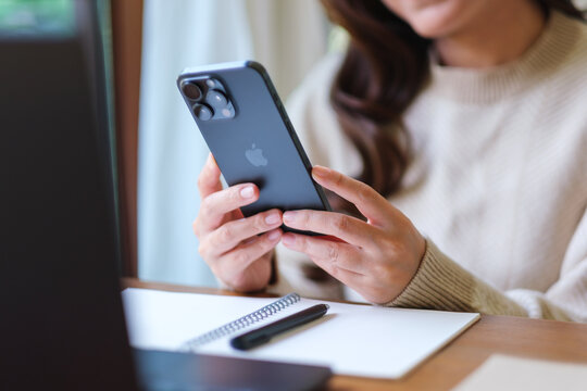 Apr 14th 2026 : A woman using Iphone 15 Pro max smartphone and laptop computer at home, Chiang mai Thailand