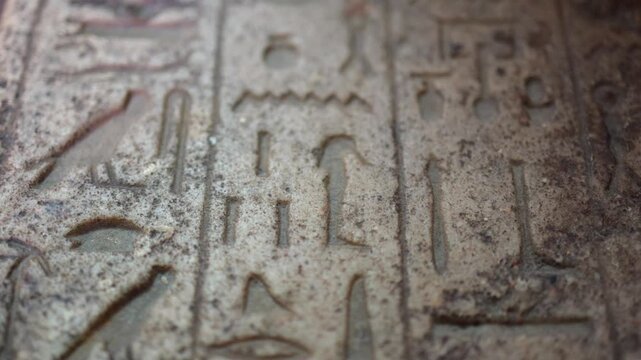 Ancient egyptian hieroglyphs and pictograms carved on a stone wall in an antique temple. Close-up view of historic scripture and symbols from the ancient civilization of egypt