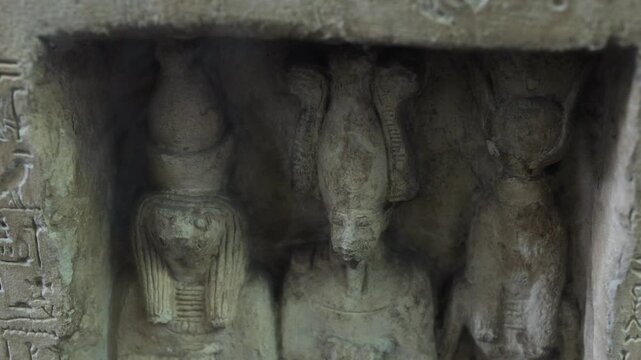Ancient egyptian stone carving depicting isis, osiris, and horus in a temple niche, a sacred artifact representing mythology, culture, and religious beliefs from antiquity