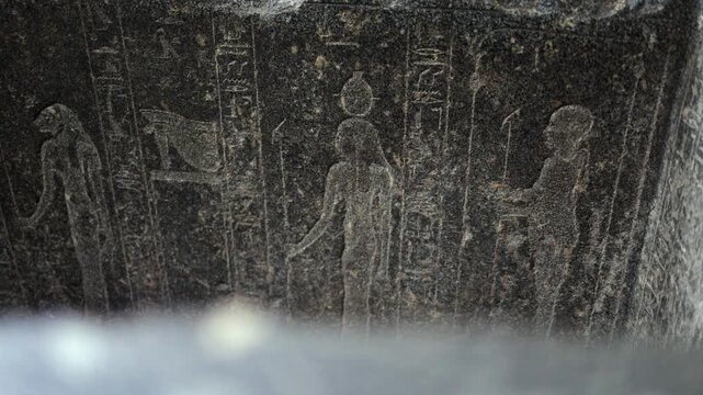 Ancient egyptian hieroglyphs carved on a black stone monument revealing figures of gods and pharaohs, representing the history and culture of ancient egypt