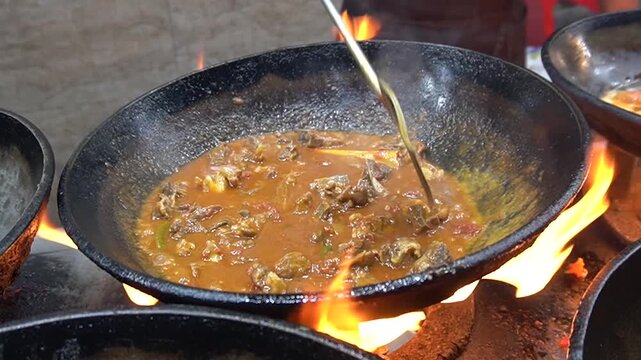 Karahi stew sizzling in wok with flames and intense heat, spicy cooking concept