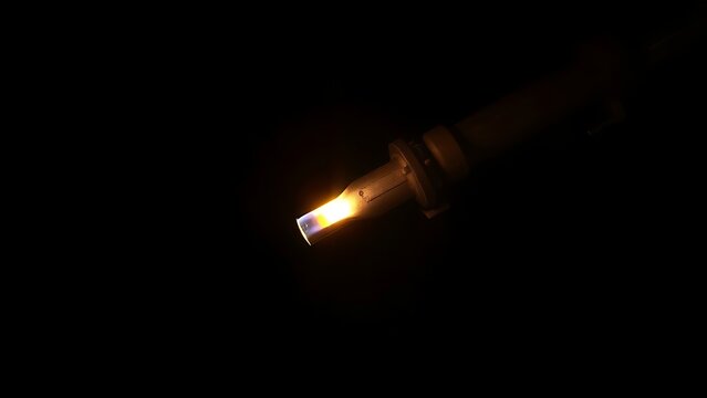 A single intense beam of cutting torch flame in complete darkness.