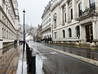 Naklejka premium Rainy London, UK street with grand historic architecture and wet reflections on pavement
