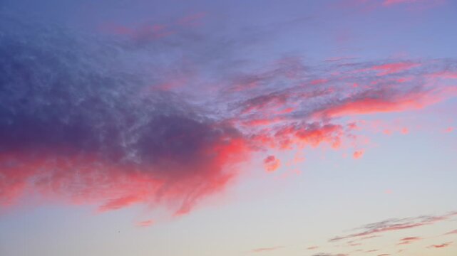 colorful pink and blue sunset clouds drifting across an open evening sky, creating a soft atmospheric background with vivid twilight tones and dramatic natural light.
