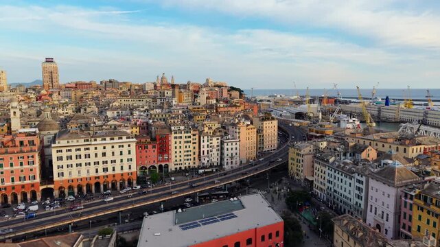 Drone push toward Porto Antico and Genoa historic center at sunset, buildings, roads and cityscape view.