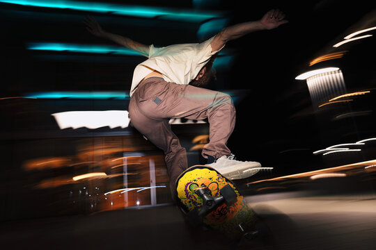 Skateboarder performing trick at night with motion blur