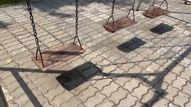 Vintage wooden playground swings on a stone paved floor
