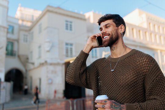 Smiling man talking on phone enjoying coffee urban street