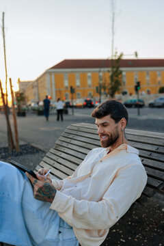 Tattooed man creating digital art on tablet outdoor