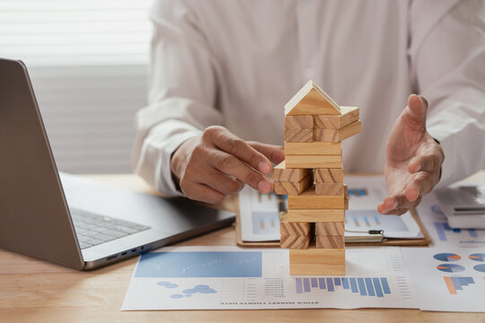 The image depicts a businessman building a tower from wooden blocks, illustrating the concept of business strategy and planning for success.