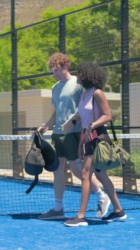 Vertical video: Finishing hug, man holding ball and bag, woman in sport clothes, walking blue court
