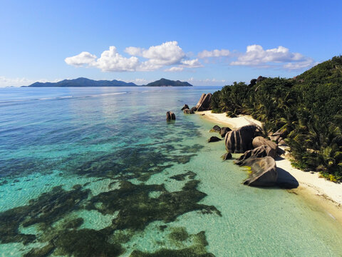 Aerial view of Anse Source d'Argent beach with turquoise water, iconic granite boulders, white sand, and lush palm trees in L'Union Estate, Seychelles.