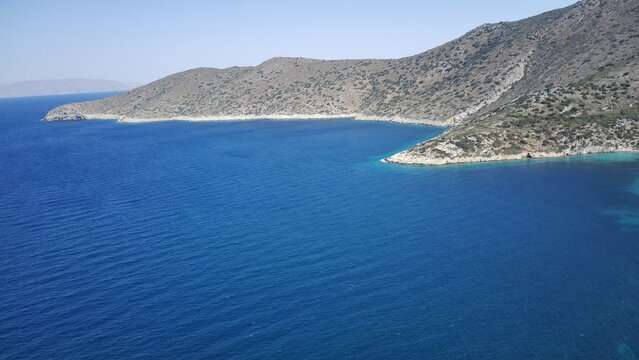 Aerial drone view of turquoise Mediterranean&ndash;Aegean waters meeting green mountains, panoramic and serene coastal landscape.