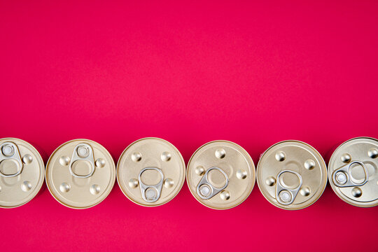 Row of metal tin cans on pink background