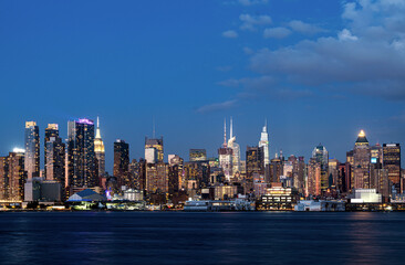 Obraz premium Panoramic view of New York City skyline with lit skyscrapers in realistic style on a dusk sky background, concept of vibrant urban evening mood
