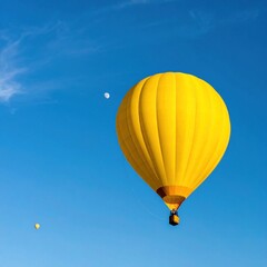 Fototapeta premium Bright yellow hot air balloon soars against a clear blue sky, exuding freedom and adventure