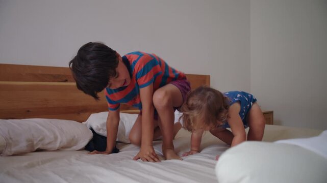 Sibling children jumping on bed with lively motion and laughter showing strong connection playful energy and authentic family interaction in comfortable home environment