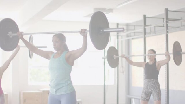 Turquoise lead starting bar lowering from overhead, guiding synced barbell pulls for strength