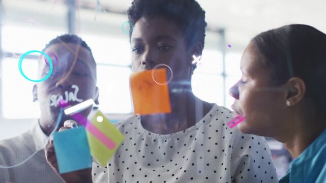 Team at glass center holding orange sticky note starting work planning writing as neon lines moving