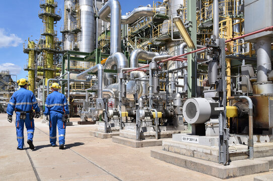 group of industrial workers in work wear in a refinery - oil processing equipment and machinery