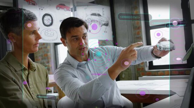 Designer man pointing at transparent display, tapping overlays, matching car model, woman observing