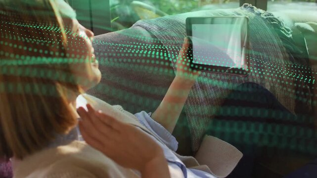 Reclining mid-adult woman lifting tablet and waving, initiating green wave tech overlay, greeting