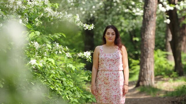 A young woman in a spring park. A beautiful woman stands near a flowering tree.