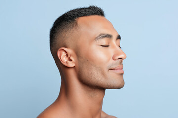 Naklejka premium Man short hair inhaling deeply focused expression soft b b calm profile portrait of young man with short hair eyes closed enjoying deep breath against pale blue background, smooth skin and relaxed