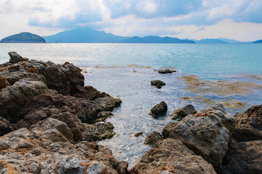Island coastal reefs, shallow waters, seaweed, and distant mountain scenery in Daya Bay, Huizhou, Ch