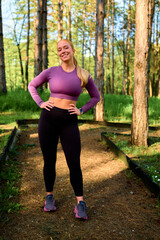 Blonde young woman wearing activewear and smiling at the camera, taking a break from her workout in...